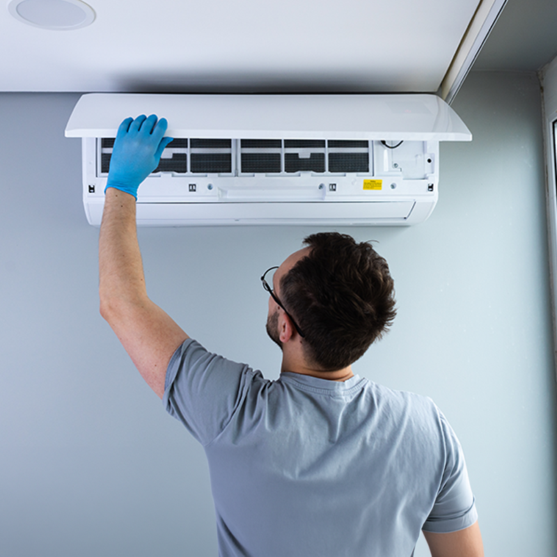 Technician performing maintenance on an indoor air conditioning unit